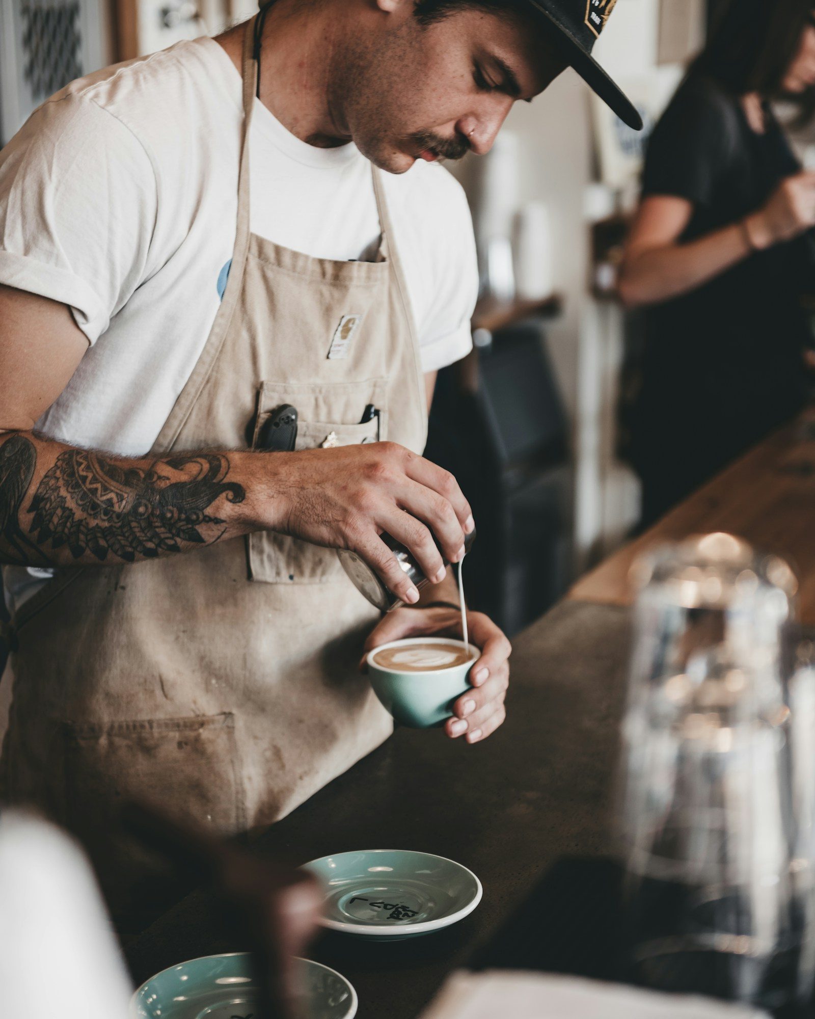 Barista sirviendo un café con leche en la barra de una cafetería